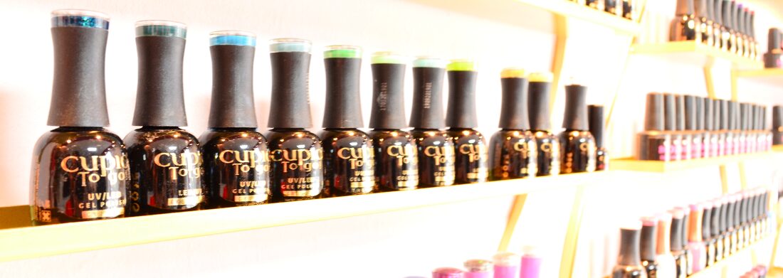 Rows of nail polish bottles on gold racks in the salon
