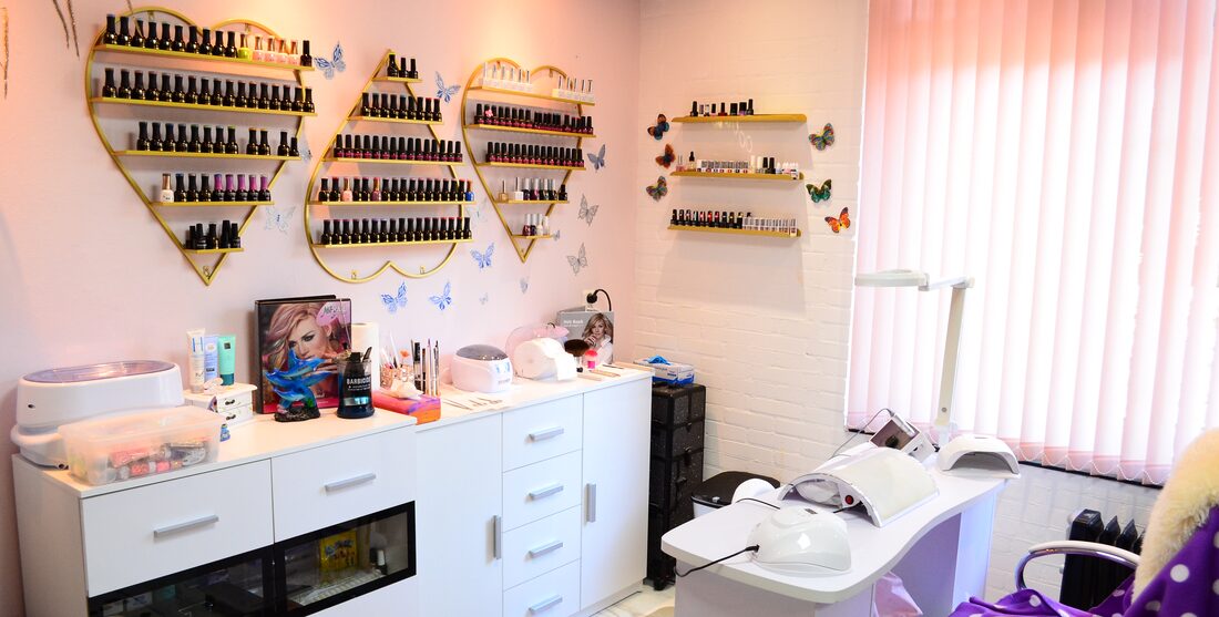 Interiorul salonului Nail Salon Michelle cu mese de manichiură și rafturi de ojă